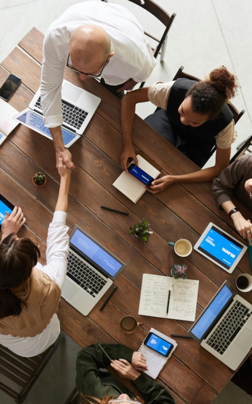 People sitting in an office working on their laptops, shaking hands