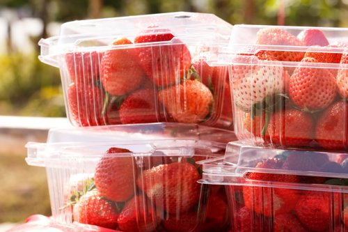 Fresh strawberries in clear plastic containers stacked outdoors