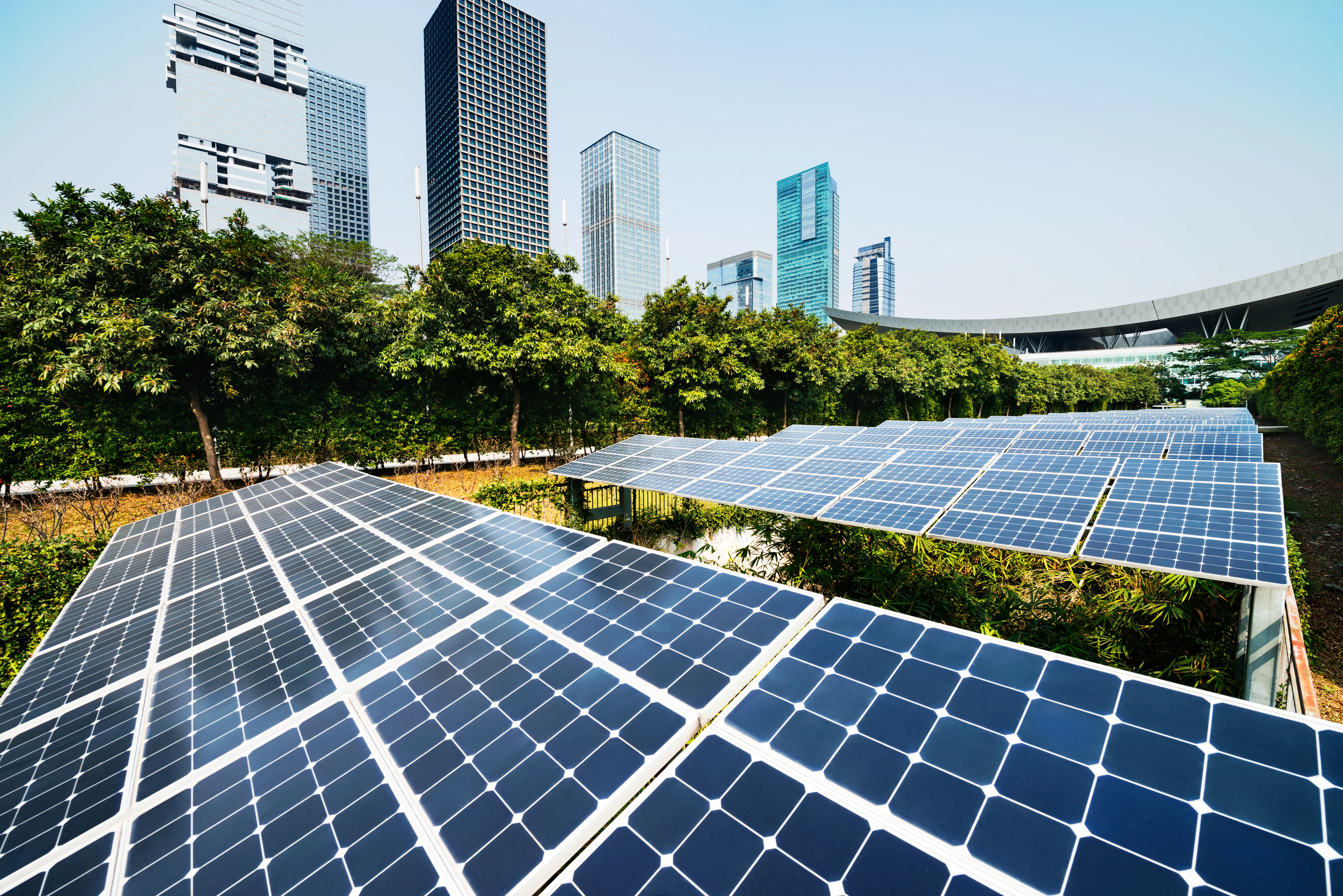 Solar panels in an urban park with modern skyscrapers in the background, showing renewable energy and sustainable city infrastructure.