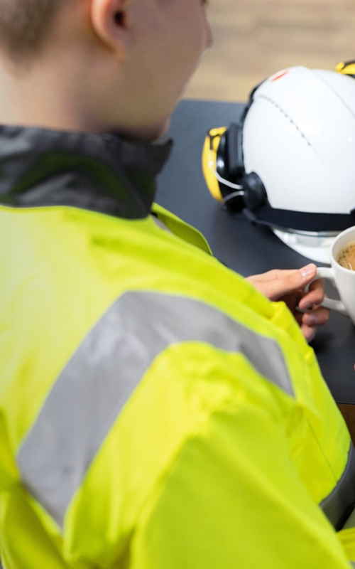 Man wearing a yellow fluorescent jacket using the Kiwa Impact™ Safety app