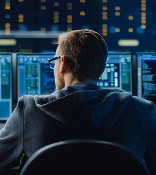 Man sitting behind multiple screens working with the Kiwa User Access Management tool
