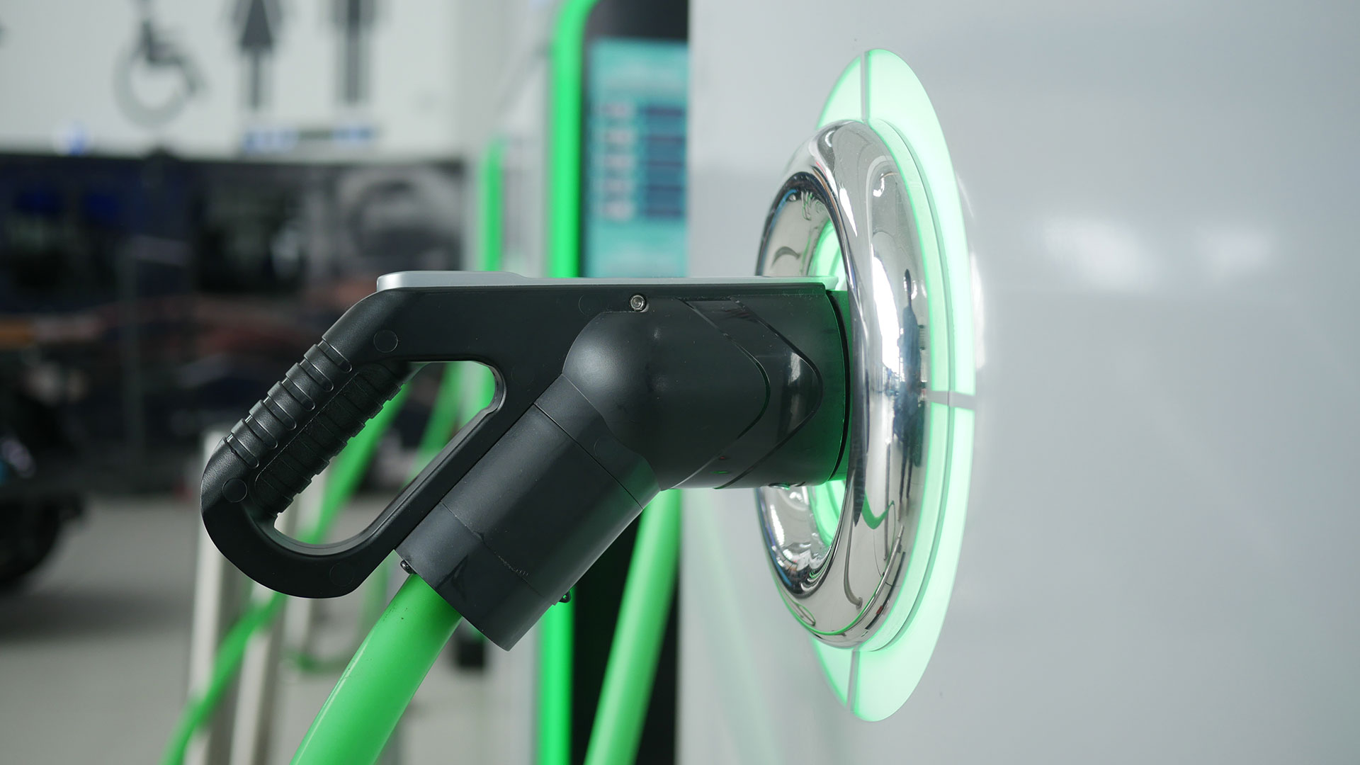 Närbild av en laddningskabel ansluten till ett elfordon vid en laddstation.