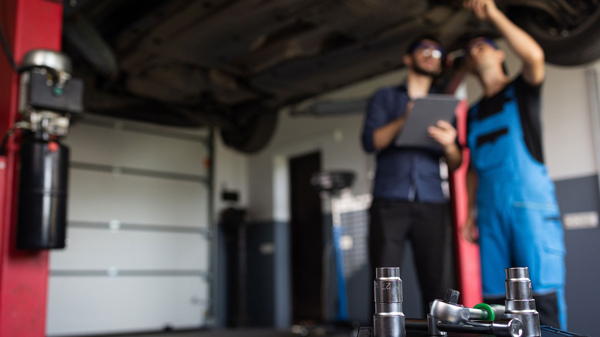Tv&aring; anst&auml;llda mekaniker diskuterar med varandra p&aring; en bilverkstad. Sermi certifiering underl&auml;ttar f&ouml;r oberoende verkst&auml;der om deras anst&auml;llda har Sermi certifikat f&ouml;r att arbetar med bilar oavsett m&auml;rke. 