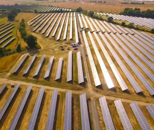 Aerial view of a large solar farm with rows of solar panels in a rural landscape.